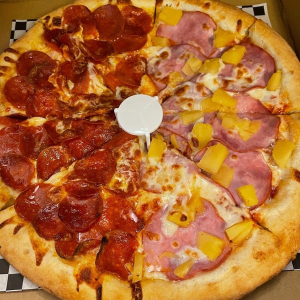 A Kraving Kebab Pizza with half pepperoni and half ham and pineapple, in a pizza box.