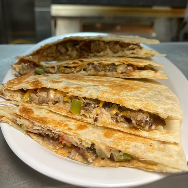 Four Kraving Kebab Pizza quesadillas, filled with meat, cheese, and vegetables, on a white plate.
