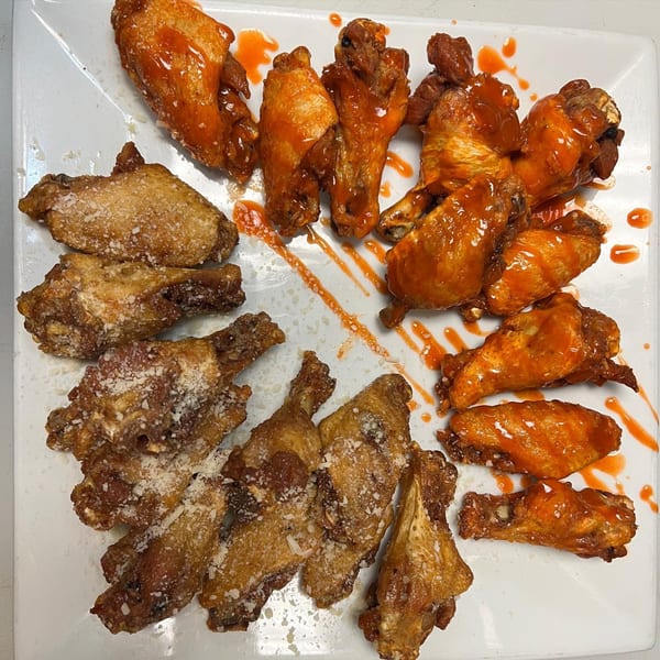 A platter of Kraving Kebab Pizza's chicken wings, half with hot sauce and half with parmesan.