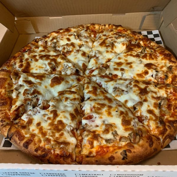 A Kraving Kebab Pizza, sliced into eight pieces, with melted cheese and toppings in a cardboard box.
